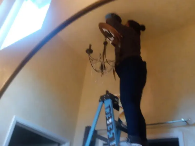 Electrician installing a chandelier in a Foley residence